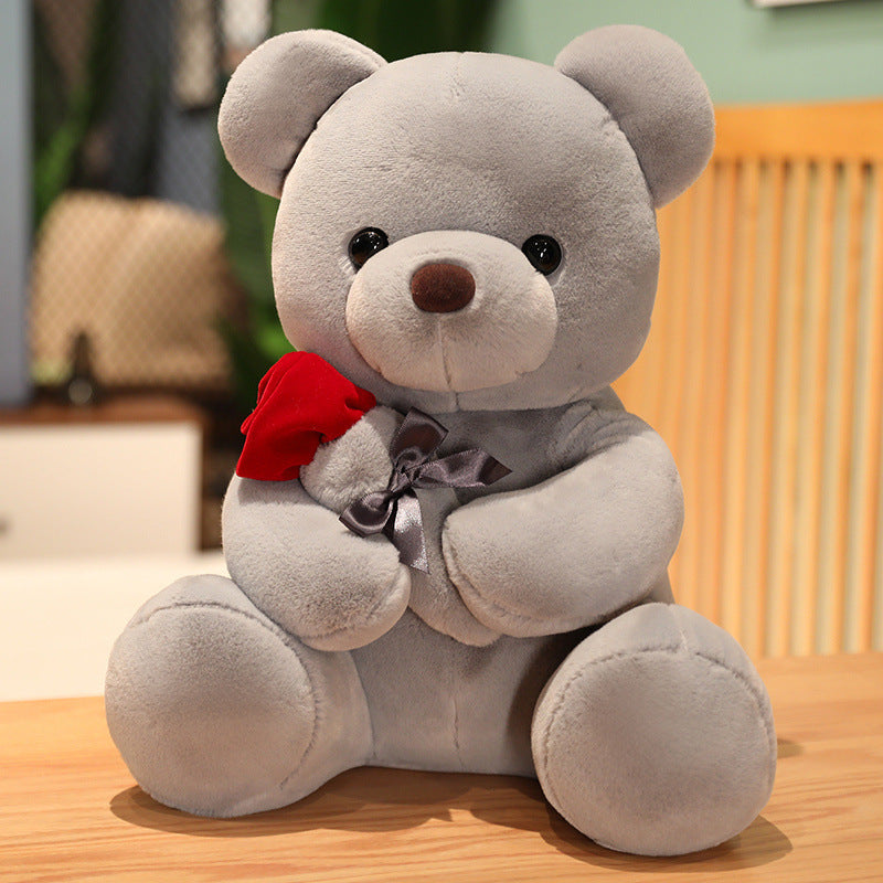 Brown teddy bear holding a red rose